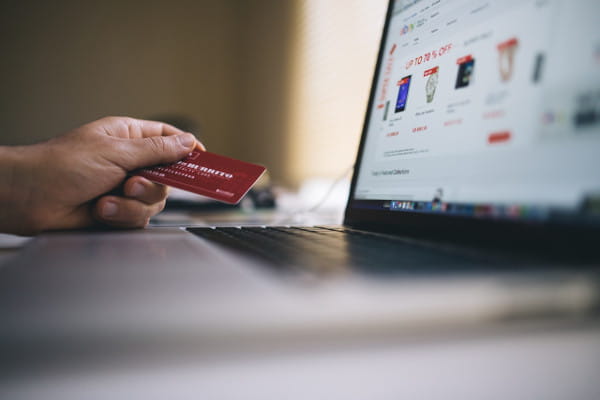 Cinco passos essenciais para abrir um e-commerce: pessoa acessando site com cartão em mãos.