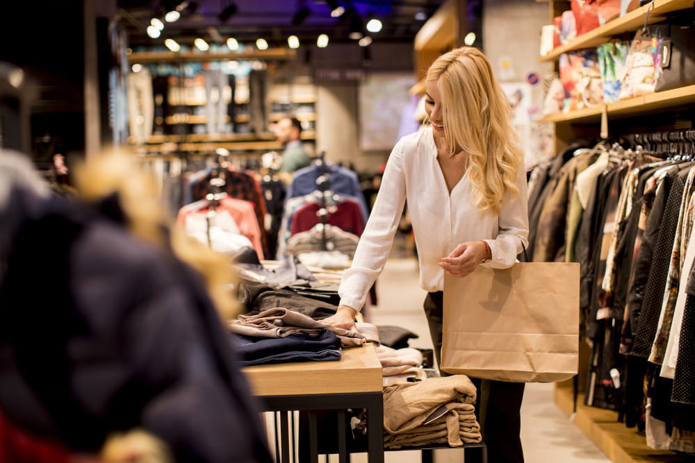 Como fazer gerenciamento de marca: mulher comprando roupas em uma loja no shopping.