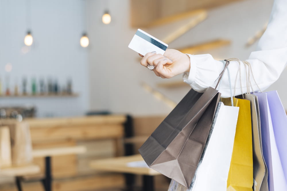 Como migrar loja física para online: mulher com sacolas e cartão de crédito nas mãos.