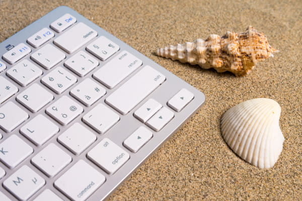 Criação de Sites em Santos: teclado na areia ao lado de conchas.