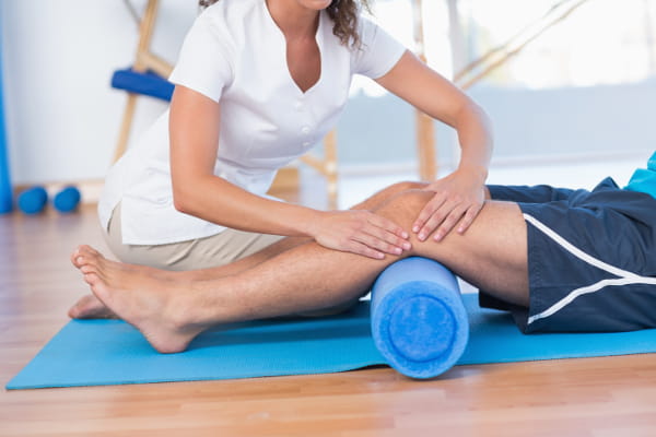 Criação de Sites para Fisioterapeutas: Homem deitado e uma fisioterapeuta avaliando o seu joelho.