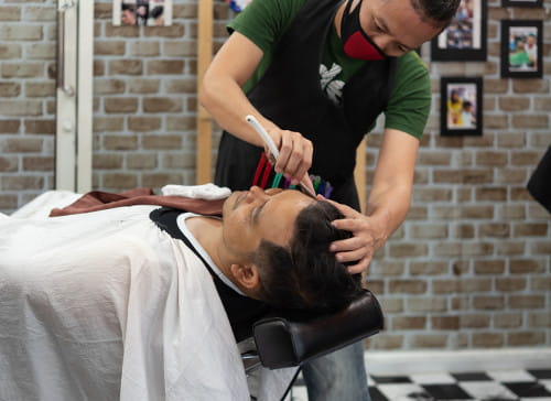 Barbeiro fazendo a barba de um cliente