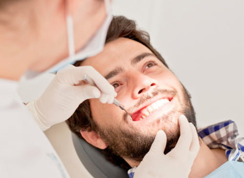 Marketing digital para dentistas: Rapaz jovem com a boca aberta, sendo examinado por um dentista.