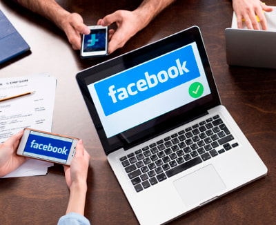 Pessoas interagindo com Facebook através de notebooks e celulares