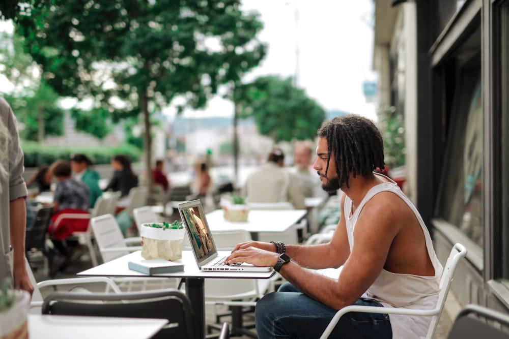 Fotografia e Vídeo: qual a importância no setor de Marketing: homem com laptop em um café.