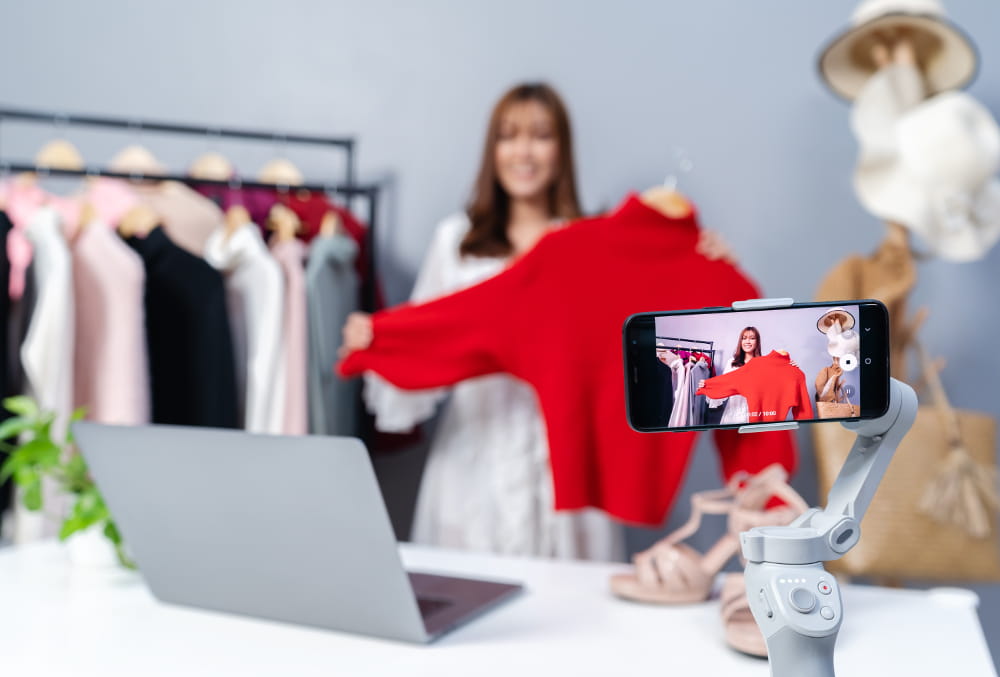 Marketing digital para loja de moda feminina: mulher filmando detalhes dos seus produtos para postar no Instagram.