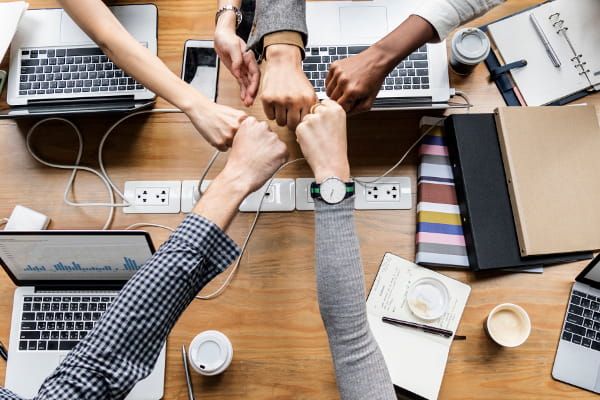 Marketing holístico: o que é e como aplicar: equipe tocando as mãos em sinal de união.