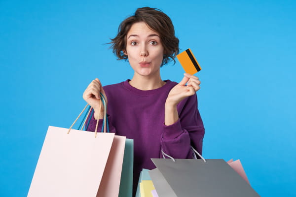 Medo da perda: como utilizar esse gatilho: mulher segurando várias sacolas e um cartão de crédito.