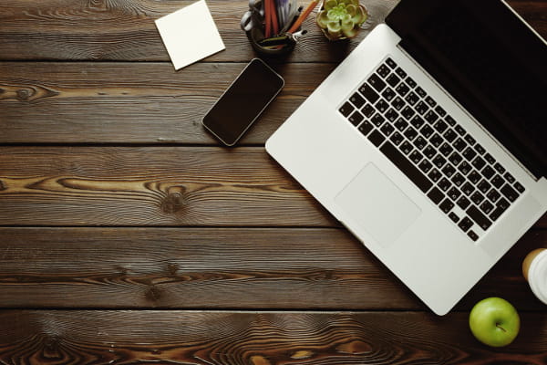 Saiba como trabalhar com o WordPress: mesa com notebook, celular, café e uma maçã.